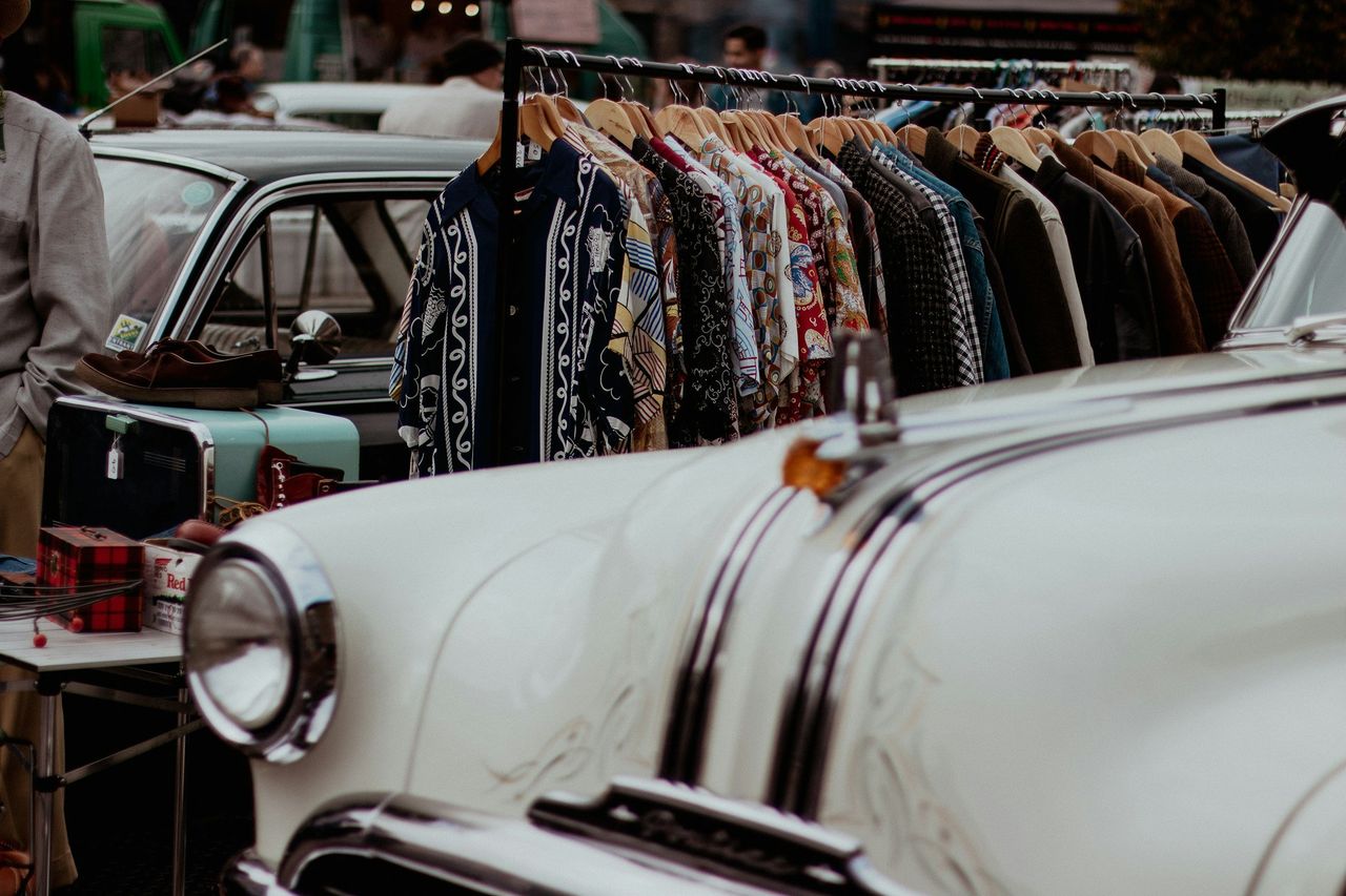 Tienda de ropa vintage. Foto: <a href="https://unsplash.com/@elliecooperphotography?utm_source=Hoy%20Apps&utm_medium=referral" target="_blank" rel="noopener">Ellie Cooper</a> (<a href="https://unsplash.com/photos/a-man-standing-next-to-a-white-car-in-front-of-a-row-of-shirts-JP30ztPaN68?utm_source=Hoy%20Apps&utm_medium=referral" target="_blank" rel="noopener">Unsplash</a>)